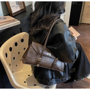Detail of vintage brown shoulder bag showing retro matte leather texture and metal buckle