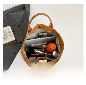 Draufsicht auf das Innere einer gelben Shopper-Tasche mit Tablet, Schirm und Kosmetik