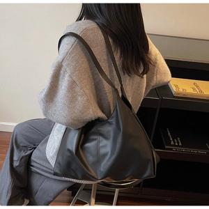 Minimalist black matte leather tote bag shown on model with vertical stitching detail