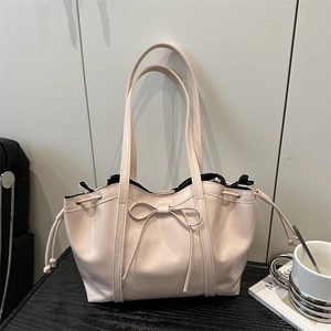 Elegant beige tote bag with ribbon bow detail and soft leather finish for women
