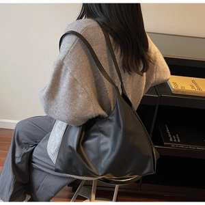 Detailed side view of a black leather tote bag with long straps and vertical stitching