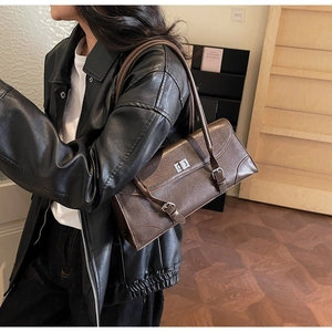 Close-up of vintage dark brown leather shoulder bag with metallic twist lock and straps