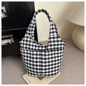 Detail of checkered canvas tote bag with front pocket showing fabric texture and pattern