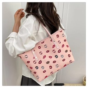 Pink faux leather tote bag with lip prints shown on shoulder for size reference
