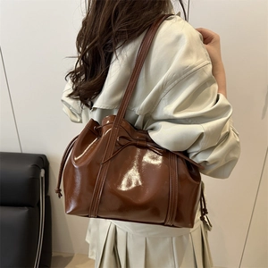 Glossy brown patent leather bucket bag with drawstring and decorative bow for women