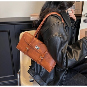 Detail view of a vintage brown leather underarm bag with silver twist lock and buckle straps