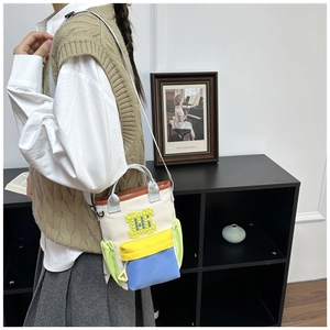 Detail of color-blocked canvas crossbody bag with pixel art blocks on female model