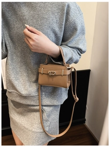 Detail der braunen Mini-Tasche aus Leder mit Litschi-Maserung und goldener Schließe