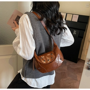 Detail of vintage brown crescent bag with rivets on shoulder strap for women