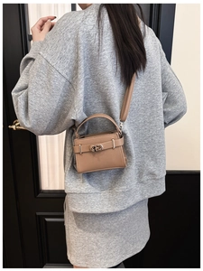 Detailansicht der khakifarbenen Mini-Handtasche aus Leder mit Drehverschluss an einem Model
