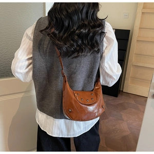 Detail of a vintage dark brown crescent hobo bag with silver studs on a female model