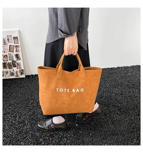 Detailaufnahme der großen senfgelben Tragetasche mit Wildledertextur und TOTE BAG Aufdruck