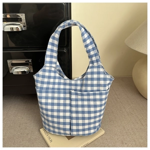 Close-up of blue and white checkered tote bag with two front pockets on a magazine
