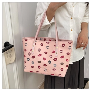 Close-up of pink tote bag featuring colorful lip prints and silver rivet hardware detail
