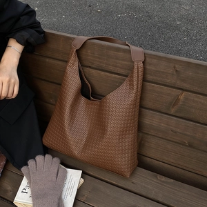 Gros plan sur la texture tressée marron et le design incurvé de ce grand sac cabas chic