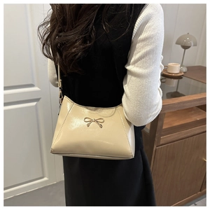 Chic beige patent leather shoulder bag featuring a delicate gold butterfly hardware detail