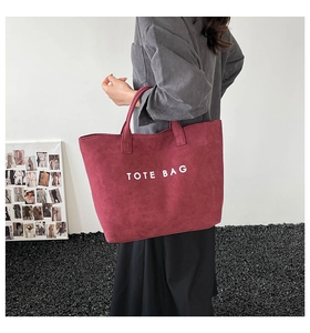 Detail der weinroten matten Tote Bag mit weißem TOTE BAG Textaufdruck und Doppelgriffen