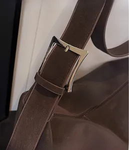 Close-up of silver metal buckle and adjustable shoulder strap on dark brown tote bag