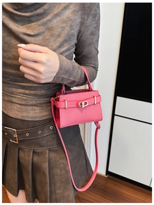 Detail der fuchsiafarbenen Leder-Minitausche mit Metalldrehverschluss und Gurt