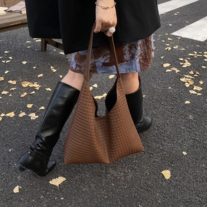 Gros plan sur la texture du sac cabas tressé marron avec bandoulière large en décor d'automne