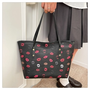 Detail of black tote bag featuring vibrant lip pattern prints and faux leather texture