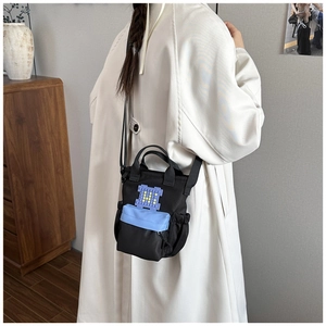 Detailed view of black nylon crossbody bag with blue zipper pocket on a model