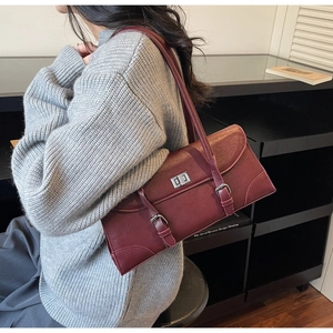 Close-up of burgundy retro baguette bag with silver twist lock on a grey sweater