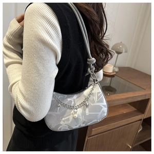 Detail view of silver crescent underarm bag with star chain and pearl charms