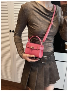 Mini-Handtasche aus pinkem Leder mit goldenem Drehverschluss am Model getragen