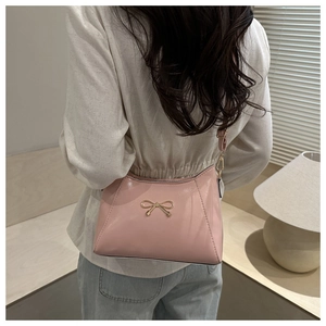 Close-up of pink shoulder bag featuring a minimalist golden butterfly metal accent