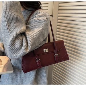 Detail of burgundy baguette bag with silver twist lock on a gray knit sweater