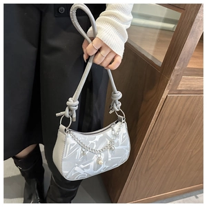 Close-up of silver glossy shoulder bag with graffiti pattern and pearl chain detail