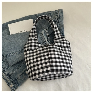 Detailed view of black and white gingham checkered tote bag on casual lifestyle setup