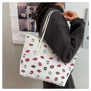 Detail of trendy cream tote bag with red lip print shown as a shoulder bag on a model