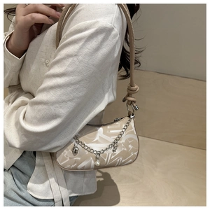 Close-up of minimalist beige printed shoulder bag with decorative heart and pearl chain