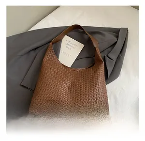 Vue détaillée de la texture du sac en cuir tressé marron et de la poignée élégante