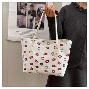 Detailed view of white leather tote bag featuring vibrant lip print and slim top handles