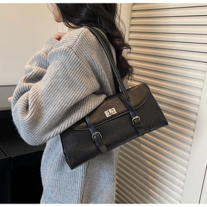 Close-up of stylish black leather baguette shoulder bag with silver metallic twist lock closure