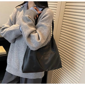 Detail of a black leather tote bag with a soft texture and spacious minimalist design