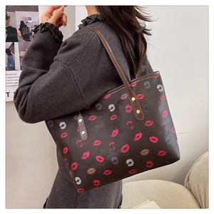 Detail of dark brown tote bag with colorful lip prints and gold rivet accents on the strap