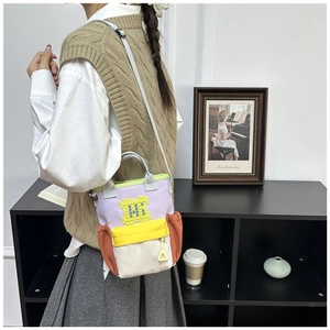 Detail of color-block oxford crossbody bag with large M letter and side pocket storage