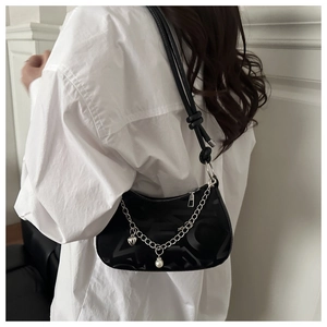 Detail of black jacquard hobo bag with silver chain, heart charm and pearl accents on model