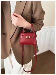 Detail der roten Mini-Handtasche aus genarbtem Leder mit goldenem Drehverschluss und Riemen