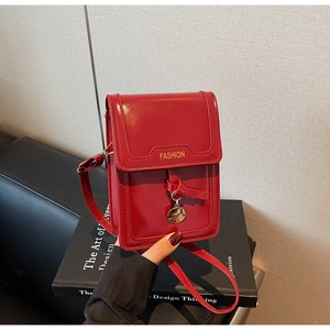 Detail of red glossy mini crossbody bag with FASHION embossment and metallic pendant