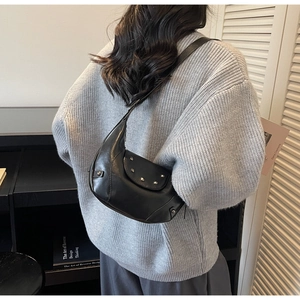 Detail of black crescent moon hobo bag with silver rivets on a grey knitted sweater