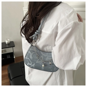 Detail of blue-gray hobo bag featuring artistic alphabet texture and silver charm chain