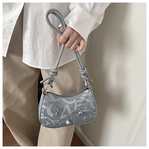 Detail of grey-blue shoulder bag with silver chain and decorative star and heart charms