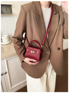 Detail der weinroten Mini-Handtasche aus Litschi-Leder mit goldenem Drehverschluss