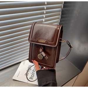 Detail of dark brown mini crossbody phone bag with gold FASHION text and metal charm