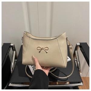 Detail of beige shoulder bag with golden butterfly buckle and neat stitching